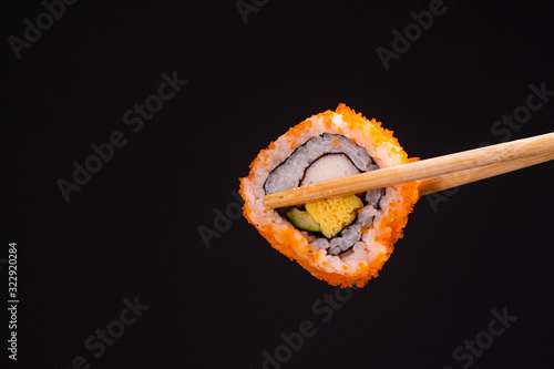 Salmon maki roll sushi nigiri in chopstick on black background