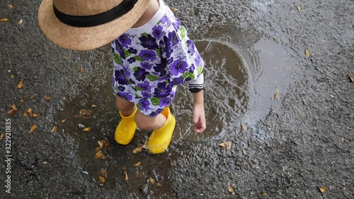 slow motion kid wearing yellow boot playing water rain puddle on road