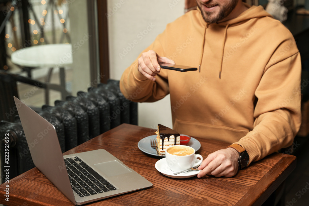 Male blogger taking photo of dessert and coffee at table in cafe, closeup Male blogger taking photo of dessert and coffee at table in cafe, closeup