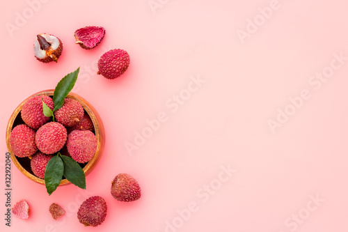 Fresh ripe lychee in bowl on pink desk top-down frame copy space photo