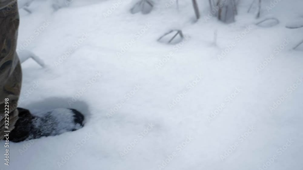 Slow-Motion tracking shot of Man walking though snow in the forest Slow-Motion tracking shot of Man walking though snow in the forest