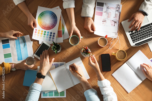 Team of professional designers working together at table, top view