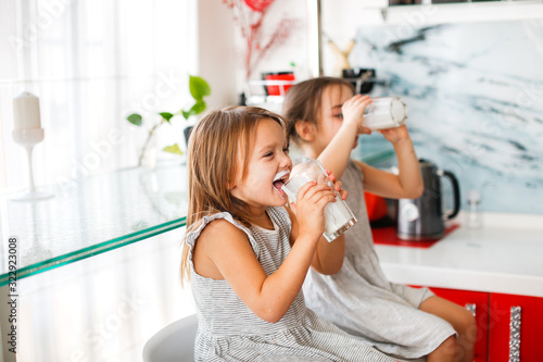 Children drink milk in a bright kitchen morning