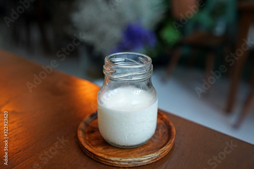 Close up glass jar of fresh milk on wooden tray table