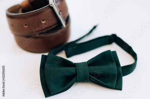 Menswear set. Men's accessories. Green bow tie and leather belt on a white background. Wedding morning