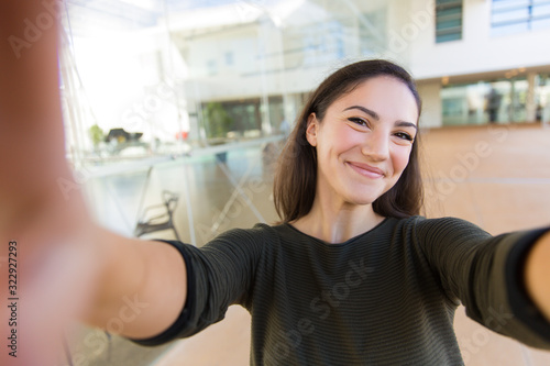 Free Download Beautiful young woman taking selfie. Smiling cheerful lady posing for self portrait. View from camera. Self portrait concept - GFXLoad