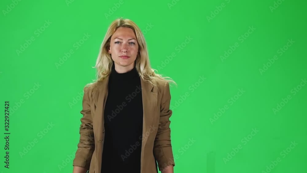 Blonde girl in a black turtleneck and stylish brown jacket going against a green screen. Slow motion Blonde girl in a black turtleneck and stylish brown jacket going against a green screen. Slow motion