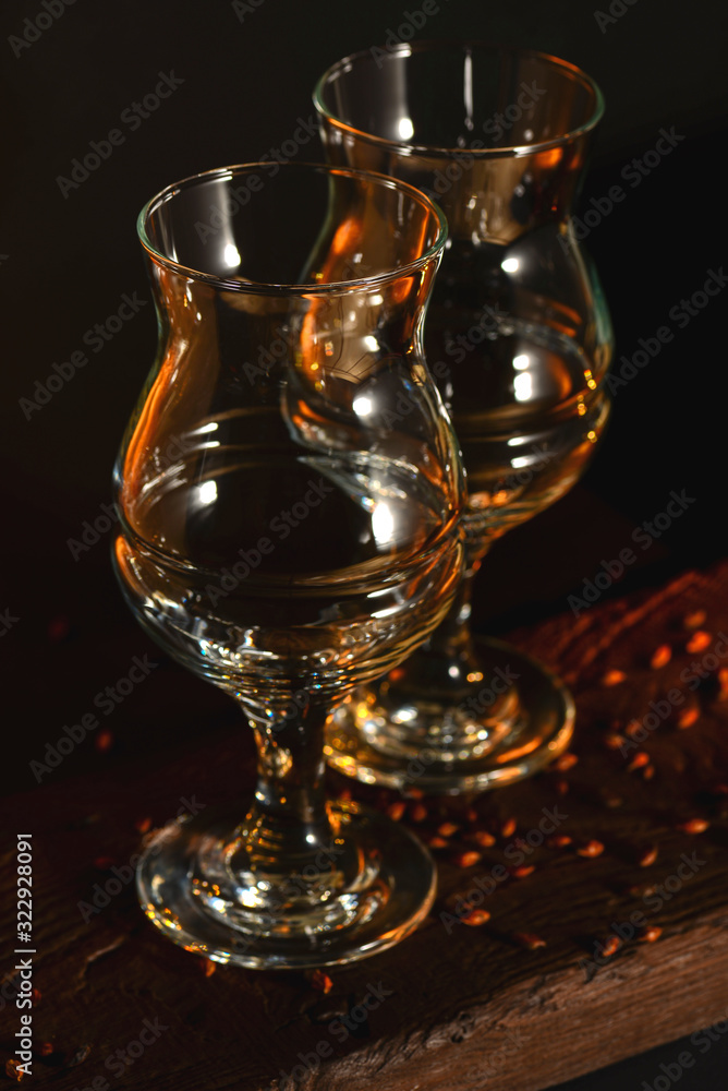 Two empty beer glasses over black background.