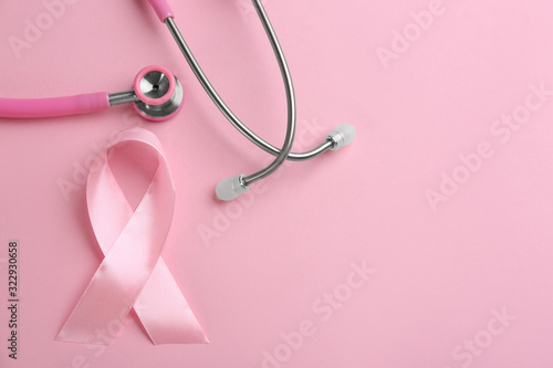 Fotografie Pink ribbon and stethoscope on color background, flat lay with space for text