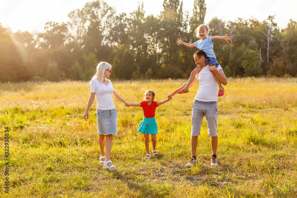Fototapeta premium Młoda szczęśliwa rodzina z dwójką dzieci w parku latem