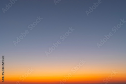 Heaven at early morning with copy space. Smooth orange blue gradient of dawn sky.Sunset, sunrise backdrop.Predawn clear sky with orange horizon and blue atmosphere. Background of beginning of day.