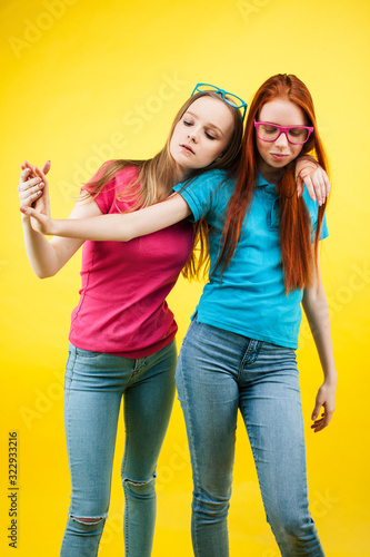 lifestyle people concept: two pretty young school teenage girls having fun happy smiling on yellow background wearing glasses