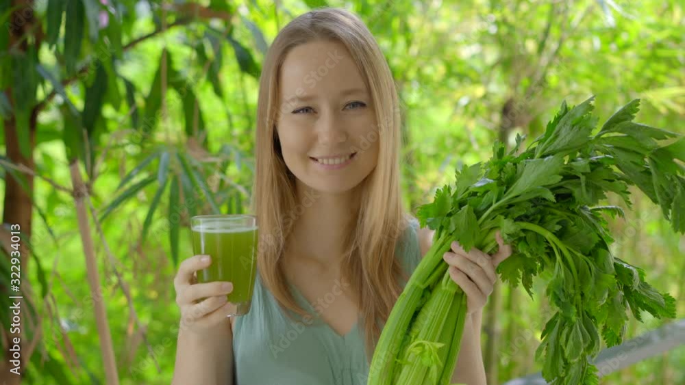 A young woman in a green environment drinks fresh celery juice A young woman in a green environment drinks fresh celery juice