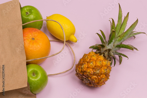 Paper bag with fruit on pink background: apple lemon grapefruit pineapple