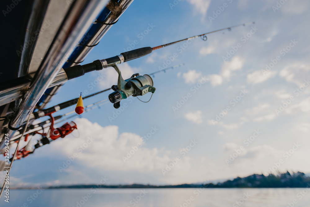 fishing rods held in fishing rod holders, attached to a back of a boat - Image