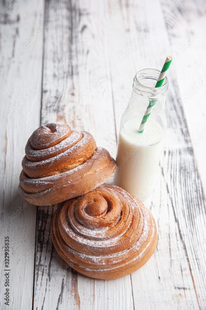 fresh homemade cinnamon rolls on a wooden cutting desk and milk in glass bottle