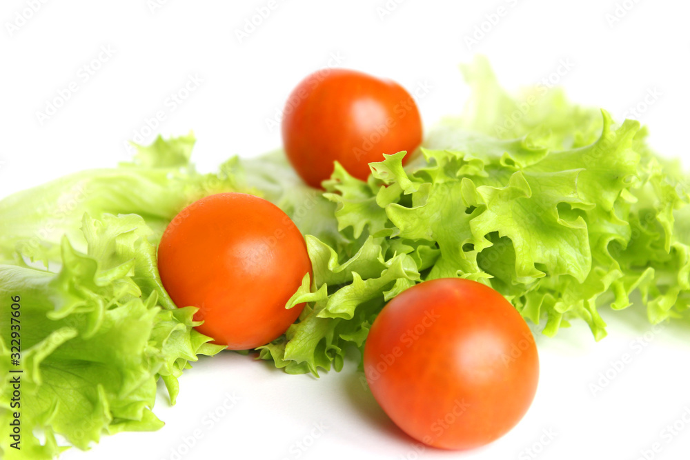 Red cherry tomatoes and lettuce leaves on white background Red cherry tomatoes and lettuce leaves on white background