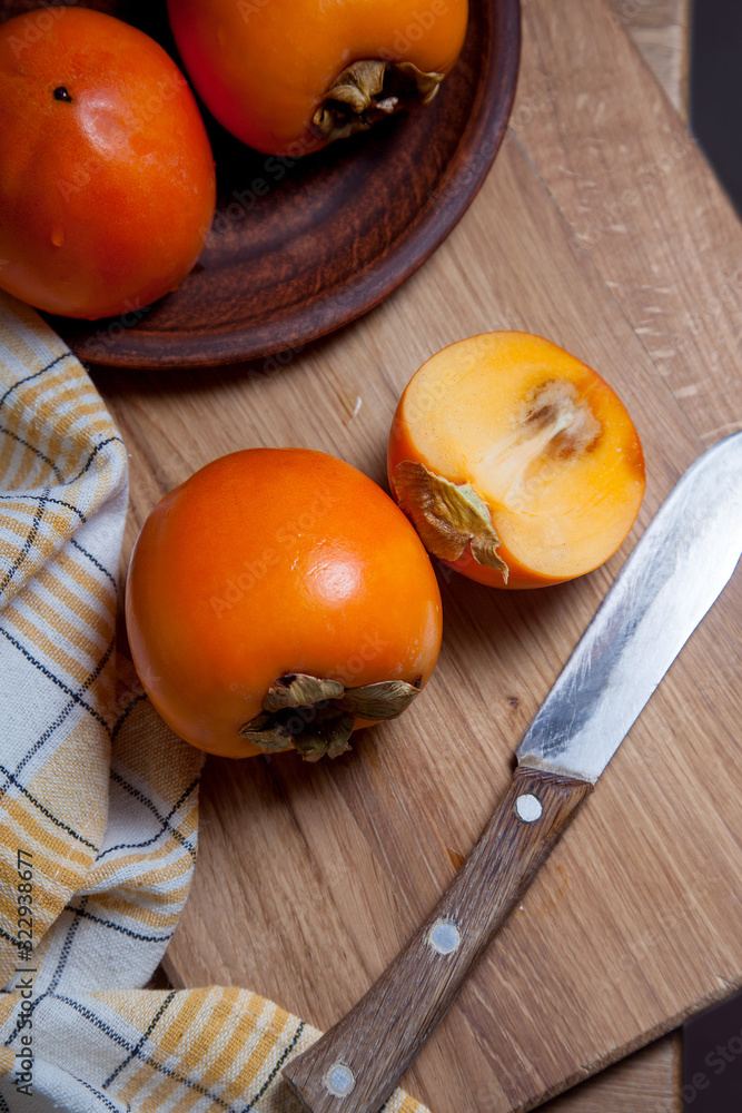 Whole ripe persimmon and sliced fruit on a wooden background.. Whole ripe persimmon and sliced fruit on a wooden background..