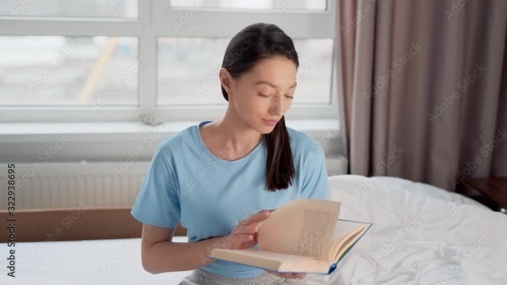 pretty girl reading a book while sitting on the bed pretty girl reading a book while sitting on the bed