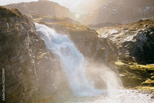 Photos Powerfull Waterfall in rugged and rocky landscape with direct sunlight