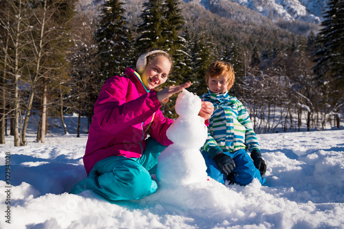 Brother and sister building a snowman together