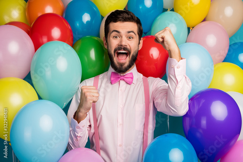 Photo of funny handsome guy different colors ready birthday party festive mood raise fists meet guests wear pink shirt bow tie suspenders on balloons creative design background