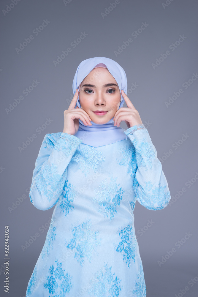 Beautiful Muslim female model wearing pastel blue modern kurung with hijab, a urban lifestyle apparel for Muslim women isolated on grey background. Beauty and hijab fashion concept. Half length Beautiful Muslim female model wearing pastel blue modern kurung with hijab, a urban lifestyle apparel for Muslim women isolated on grey background. Beauty and hijab fashion concept. Half length