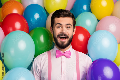 Photo of funny crazy guy open mouth colorful design atmosphere surprised birthday party formalwear pink shirt bow tie suspenders on bright many balloons creative background