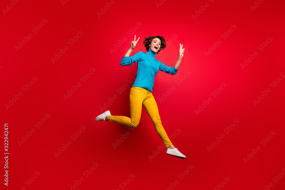 Full size photo of cheerful candid girl jump enjoy autumn spring weekends make v-sign swear good look blue clothing isolated over bright color background