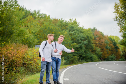 Hitchhiking gesture. Begin great adventure in your life with hitchhiking. Company friends travelers hitchhiking at road nature background. Travellers on their way. Friends hitchhikers travelling