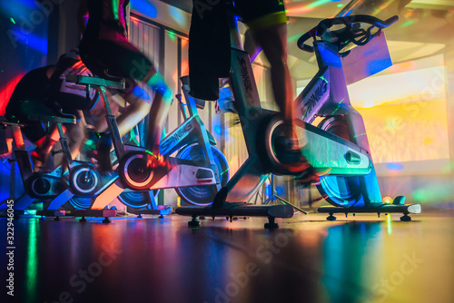 Fototapeta Spinning class, group activity on stationary bike. Team cardio excercise on bicycle.
