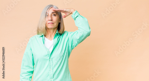 middle age cool woman greeting the camera with a military salute in an act of...