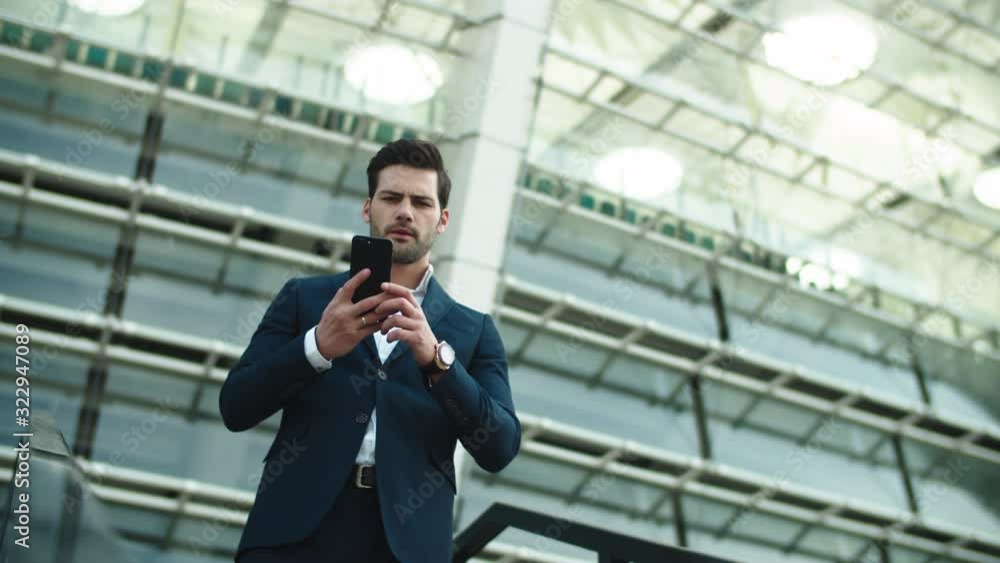 Closeup businessman picking up phone. Man standing in luxury suit near stadium Closeup businessman picking up phone. Man standing in luxury suit near stadium