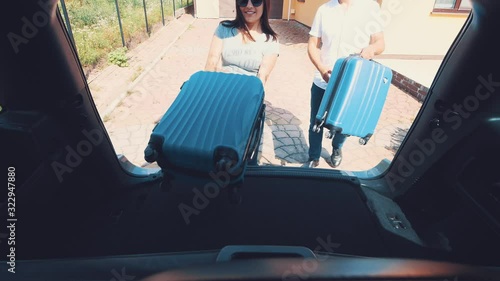 Happy man and woman take off suitcases fromthe car boot. Close up. Copy space. 4K. photo