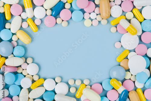 Assorted colorful medicine pills on blue background with copy space