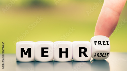 Hand turns dice and changes the German expression "mehr Arbeit" ("more work") to "mehr frei" ("more spare time").