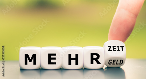 Obraz na płótnie Hand turns dice and changes the German expression mehr Geld (more money) to mehr Zeit (more time)