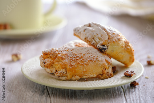 Fresh and rouge rolls with nuts, raisins and meringues on a wooden table and a cup with aromatic coffee