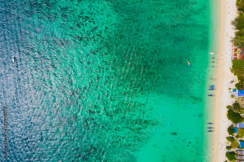 View from above, stunning aerial view of a beautiful tropical beach with white sand and turquoise clear water, long-tail boat and people sunbathing,Long beach, Phi Phi Thailand.