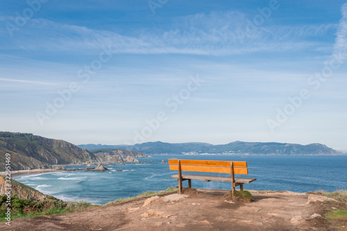 Fotografi wooden bench overlooking a cliff of rocks that overlook the blue ocean with soft