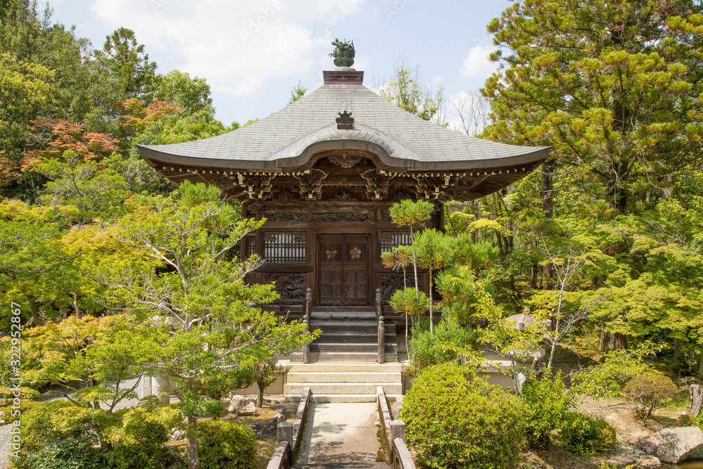 Obraz premium Photograph of the front of a Japanese wooden temple surrounded by plants