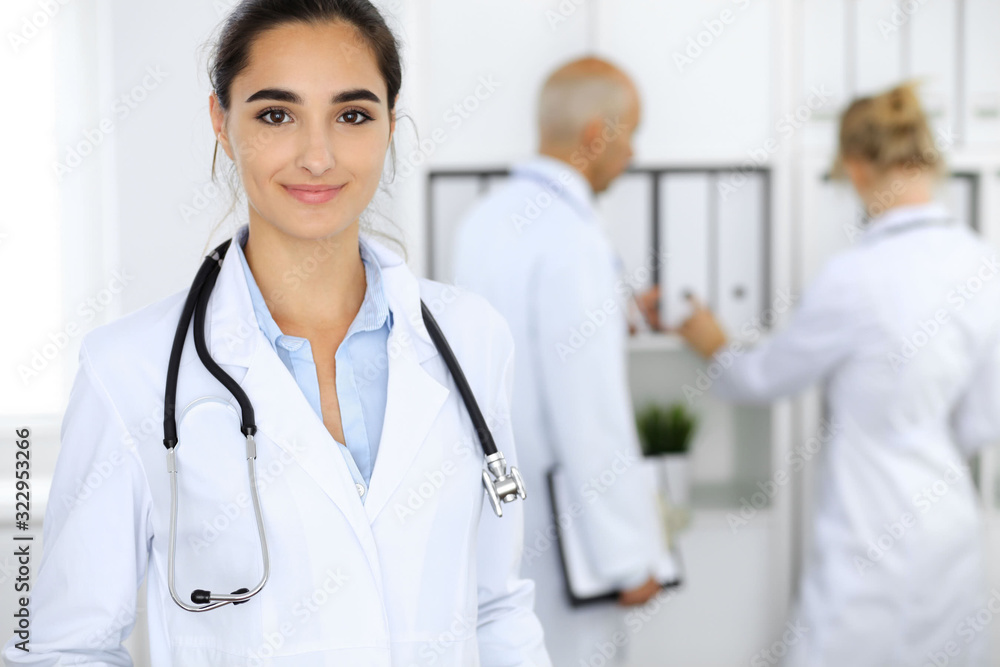 Doctor woman in clinic with colleagues at the background. Hispanic or latin american staff in medicine Doctor woman in clinic with colleagues at the background. Hispanic or latin american staff in medicine