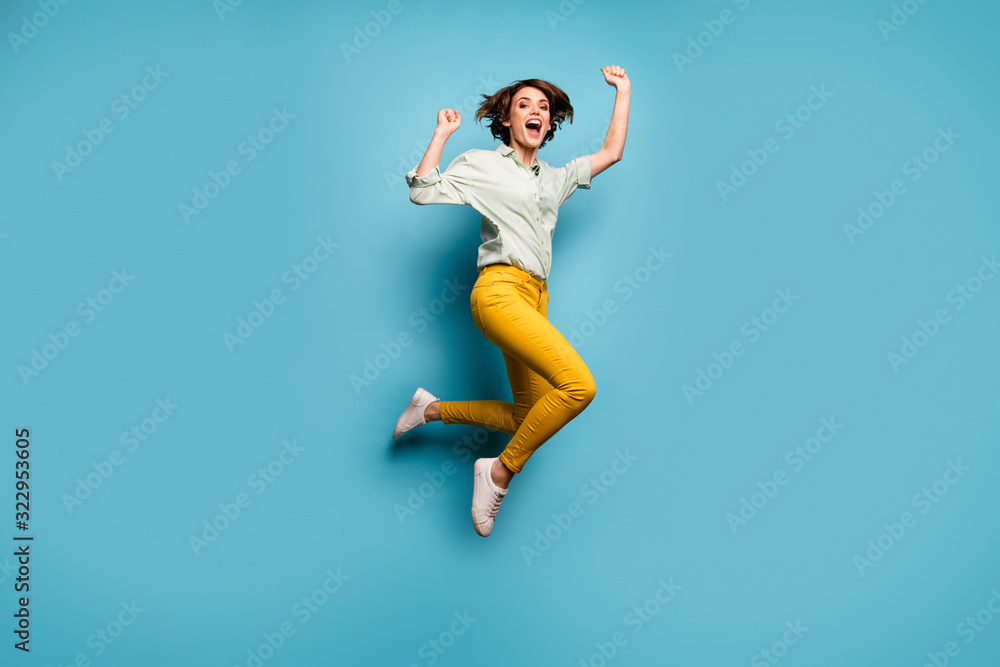 Full size photo of funky lady jumping high up celebrating weekend vacation start beginning wear casual green shirt yellow pants shoes isolated blue color background