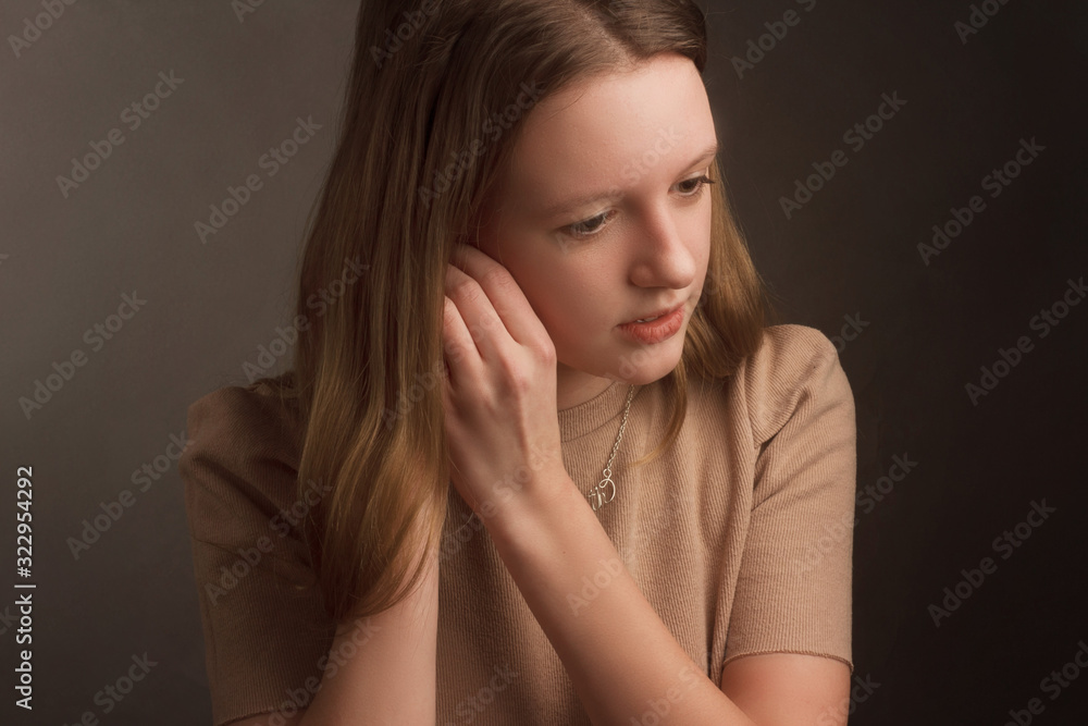 portrait of a model brown-haired in a white dress on a dark background in the Studio. fastens the earring, hands at the ear portrait of a model brown-haired in a white dress on a dark background in the Studio. fastens the earring, hands at the ear