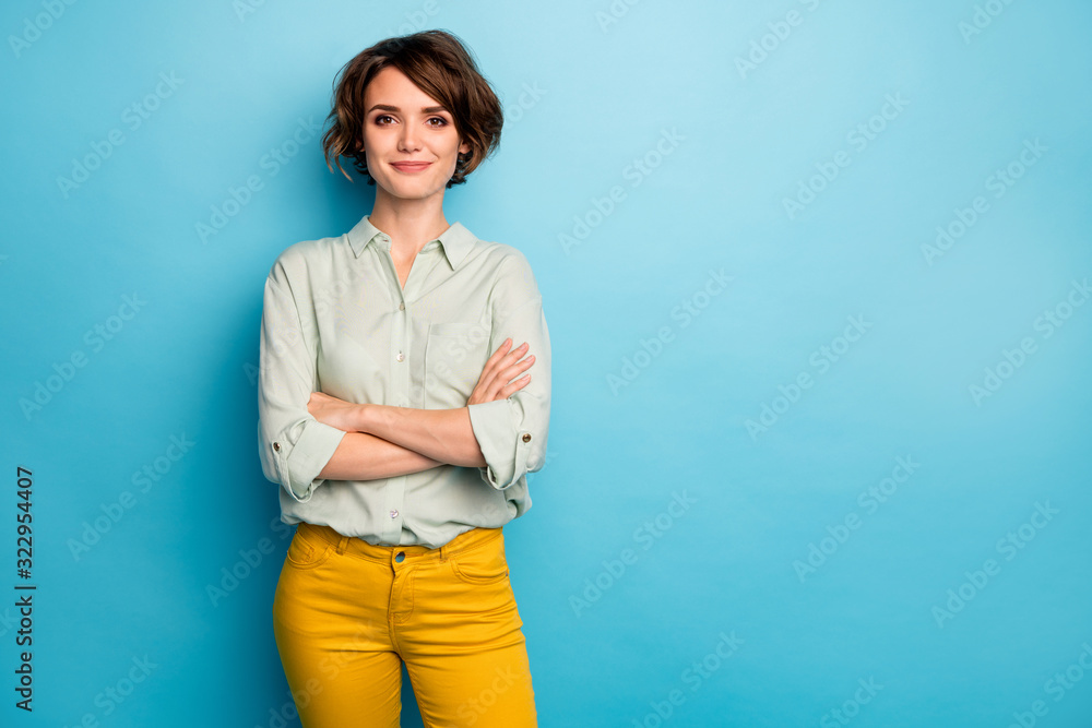 Photo of cool attractive business lady short hairstyle friendly smiling responsible person arms crossed wear casual green shirt yellow pants isolated blue color background - obrazy, fototapety, plakaty 