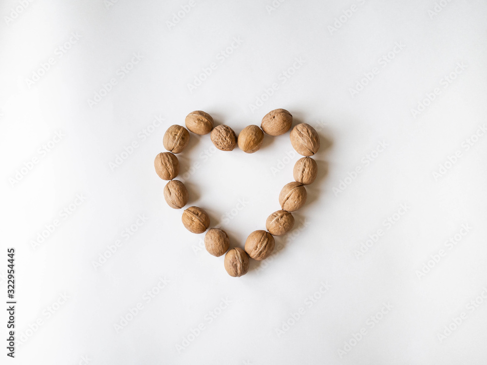 In shell walnuts in a heart shape on a white background. Top view In shell walnuts in a heart shape on a white background. Top view
