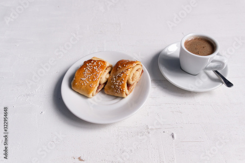 cup of coffee and saucer with dessert on white concrete background