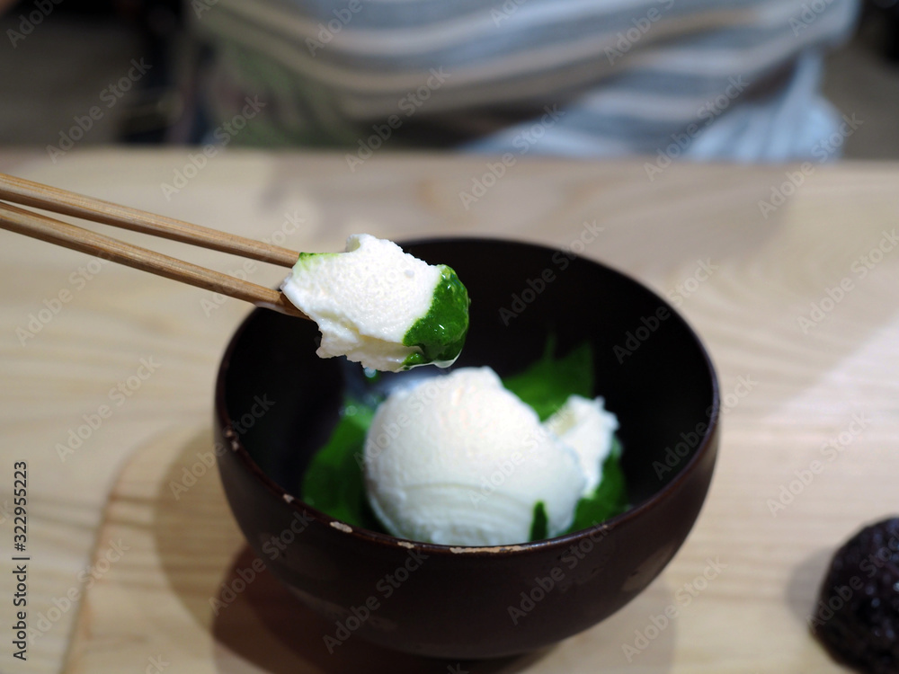 A bowl of fresh milk ice cream flavored over green tea or Japanese matcha on wooden tray. A bowl of fresh milk ice cream flavored over green tea or Japanese matcha on wooden tray.