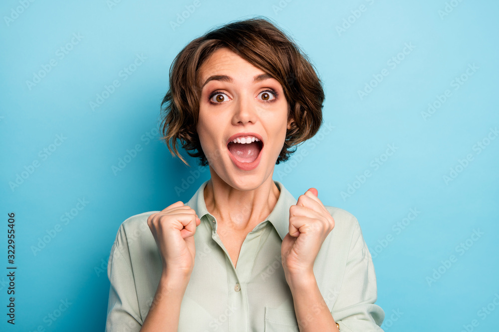 Closeup photo of funny excited lady raise fists screaming loudly celebrating money lottery winning wealthy rich person wear casual green shirt isolated blue color background Closeup photo of funny excited lady raise fists screaming loudly celebrating money lottery winning wealthy rich person wear casual green shirt isolated blue color background