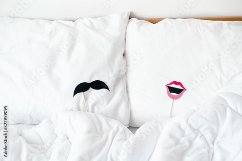 Props with lips for women and mustache for men for a stick party lie on the pillows. Content for honeymooners and lovers for Valentine's Day. photo